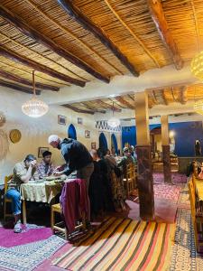 a group of people sitting at a table in a restaurant at Merzouga Hotel Activities in Merzouga