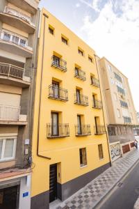 a yellow building with balconies on a street at Apartamentos La Búsqueda in Cuenca