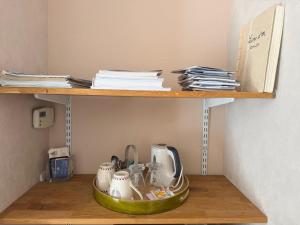 a shelf with cups and utensils in a room at La brèche fleurie in Cricquebœuf