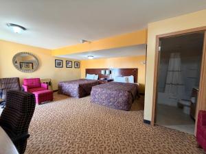 a hotel room with two beds and a chair at Regal Inn Coffeyville KS US 169 in Coffeyville