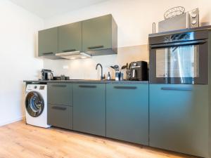 a kitchen with blue cabinets and a washing machine at Zeitwohnstudios work & stay - modern, vollausgestattet für Selbstversorger in Koblenz