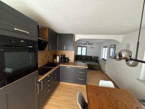 a kitchen with black cabinets and a wooden table at Bergliebe in Weitnau