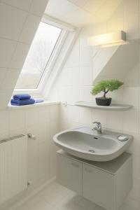 a white bathroom with a sink and a window at Kleine Auszeit Pellworm in Pellworm +12 photos