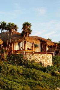 a house with palm trees and a stone wall at Papaya Playa Project, Tulum, a Member of Design Hotels in Tulum