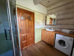 a bathroom with a washing machine and a wooden door at Domy z Bali nad jeziorem - Leśna Oaza in Międzyrzecz