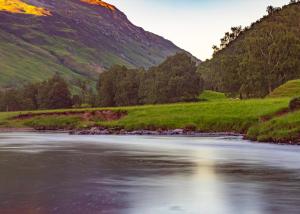 a river with a mountain in the background at Benview Lodges in Kemnay