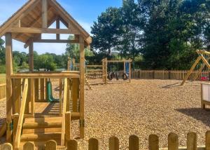 a playground with two swings and a wooden structure at Woodland Waters in Ancaster