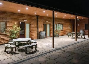 a patio with tables and benches in front of a building at Woodland Waters in Ancaster