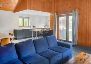 a living room with a blue couch and a kitchen at Woodland Waters in Ancaster +6 photos