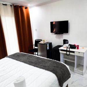 a hotel room with a bed and a desk and a tv at Rest & Digest in Serowe