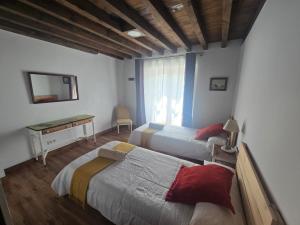 a bedroom with two beds and a desk and a window at La Casona del Rio Abion in Valdealvillo