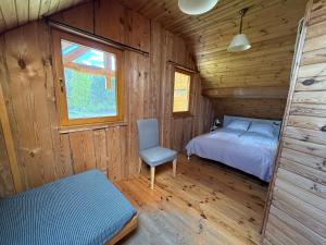 a bedroom in a wooden cabin with a bed and a chair at Domy z Bali nad jeziorem - Leśna Oaza in Międzyrzecz