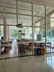 a dining room with tables and chairs and windows at Apart Itacuruçá - Hotel Porto Marina in Mangaratiba
