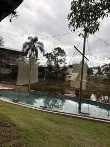 a swimming pool with two palm trees and a building at Pousada Maria elza in Eldorado