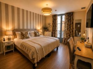 a bedroom with a bed and a desk and a window at Hôtel des Augustins - Boutique Hôtel - Restaurant Gastronomique in Saint-Cyprien