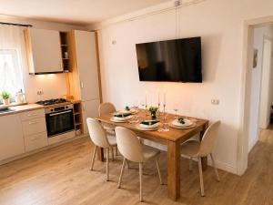 a dining room table with chairs and a television on the wall at Apartament Nou & Modern în Rădăuți 2 Camere Parcare WiFi in Rădăuţi +2 photos