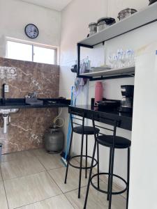 a kitchen with a black counter and stools at Rosy Flat 1 Andar in Petrolina