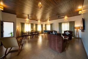 a living room with couches and a dining room at Elegant holiday homes Coorg in Somvārpet