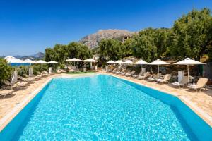 a pool at a resort with chairs and umbrellas at Nissaki Sea View Hotel in Corfu