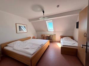 a bedroom with two beds and a table in it at W&P Living Zi 5 Bräustüble FeWo 1 2OG l in Buttenwiesen