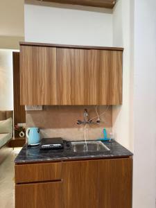 a kitchen with a sink and wooden cabinets at The Orion Nest in Noida
