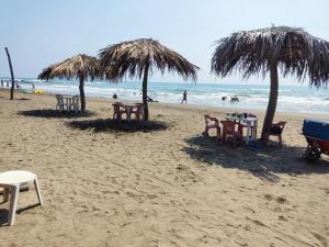 a beach with tables and chairs and umbrellas at Centro turístico la playitaa in Chachalacas