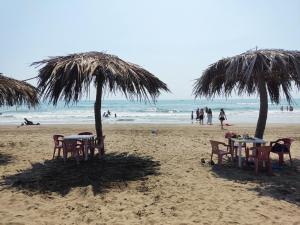two tables and chairs under two umbrellas on a beach at Centro turístico la playitaa in Chachalacas +5 photos