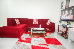a living room with a red couch and a rug at Cozy studio at Kisimani Heights Apartment Mombasa in Mombasa