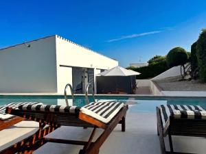 a swimming pool with two lounge chairs next to a house at Apartamento Binibeca Nou Cami de Cavalls in Binibeca