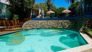 a large blue swimming pool next to a stone wall at ZAG Coliving Punta del este in Punta del Este