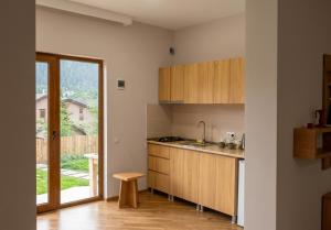 a kitchen with wooden cabinets and a door to a yard at Mountain Horizon in Borjomi
