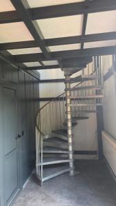 a metal spiral staircase in a room with a door at Hangar Hangout by the Lake in Priles