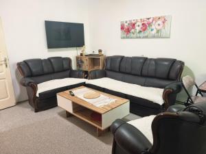 a living room with black leather couches and a table at Artisan Center Apartment Peja in Peje