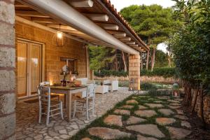 a patio with a table and chairs under a roof at Villa con piscina Seychelles del Salento in Marina di Pescoluse