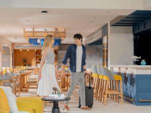 a man and a woman walking through a restaurant at ibis Styles Phuket Bangtao in Bang Tao Beach