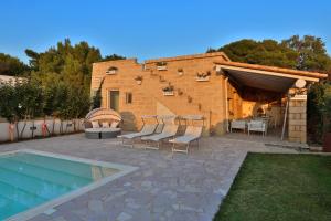 a patio with chairs and a pool in front of a building at Villa con piscina Seychelles del Salento in Marina di Pescoluse