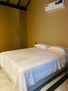 a bedroom with a white bed and a air conditioner at Villa Coco e Sol - Casa com Jacuzzi in Amontada