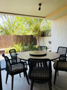 a dining room table and chairs with a palm tree at Villa Coco e Sol - Casa com Jacuzzi in Amontada