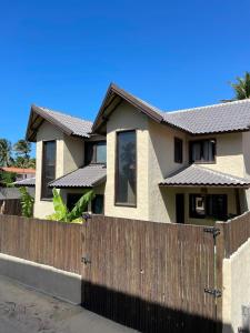 a house with a wooden fence in front of it at Villa Coco e Sol - Casa com Jacuzzi in Amontada