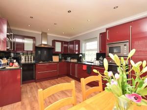 a kitchen with red cabinets and a wooden table at 2 Bed in Morpeth oc-36925 in Widdrington