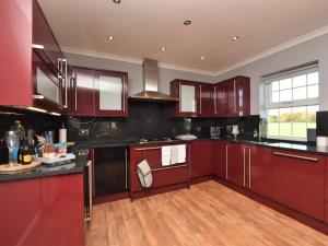 a kitchen with red cabinets and a wooden floor at 2 Bed in Morpeth oc-36925 in Widdrington