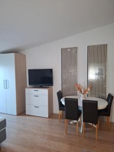a dining room with a table and chairs and a tv at Apartmani MM in Tkon