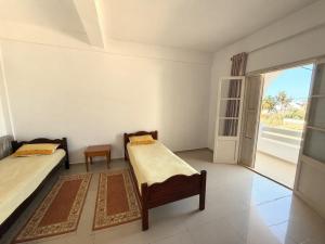 a room with two beds and a large window at Résidence Mestaoui in Houmt Souk +3 photos