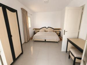 a white bedroom with a bed and a mirror at Résidence Mestaoui in Houmt Souk