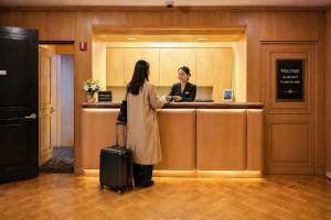 a woman standing at a hotel counter with her luggage at The Buckingham Hotel in Chicago