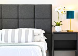 a bed with a black and white headboard and a table with a lamp at APPARTAMENTI LEONE - Vista Mare - Pet Friendly in Rimini