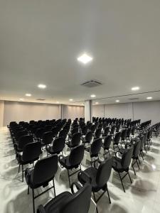 an empty room with black chairs in a building at Hotel Bonfim in Silvânia