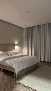 a bedroom with a large white bed and curtains at شقة ذا لوكس لوفت 2 in Buraydah