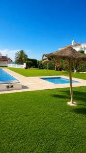 an umbrella in the grass next to a swimming pool at Casa rody in Benalmádena