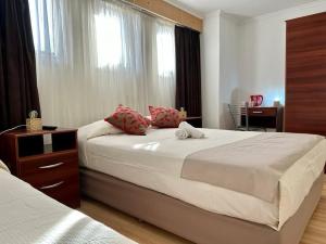 a bedroom with two beds and a desk and a window at KELMAN Hotel in Perito Moreno